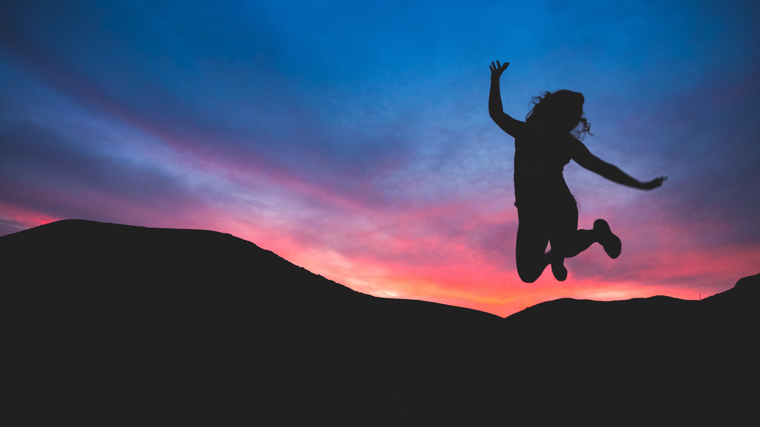 Silhouette girl jumping at sunset